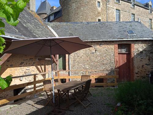 a table with an umbrella in front of a building at Charming detached 2 bedroom ancient house in medieval quarter of a small town in the Pays de la Loire, France in Sillé-le-Guillaume
