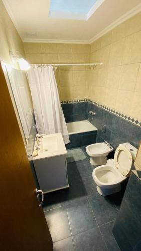 a bathroom with two toilets and a sink and a tub at Duplex Sarmiento in Olavarría