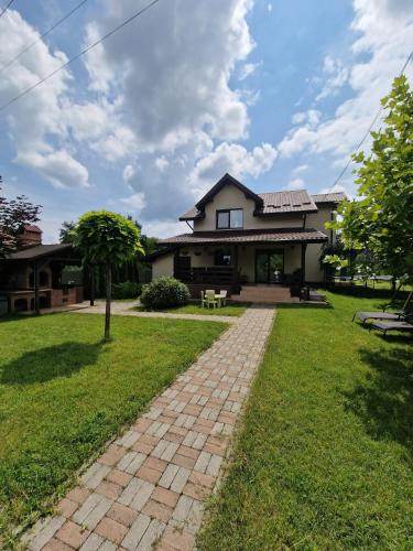 a house with a brick pathway in front of it at Casa din Deal in Păuşeşti-Măglaşi