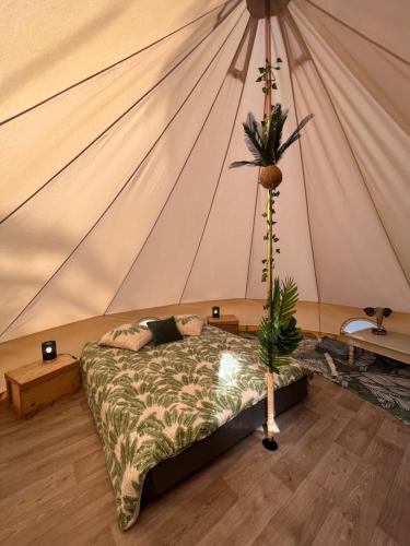 a bedroom with a bed in a tent at Le Tipi Tropical au bord de la rivière in Mios
