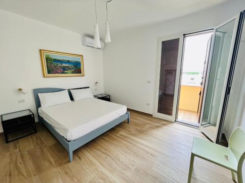 ein weißes Schlafzimmer mit einem Bett und einem großen Fenster in der Unterkunft MAVÌ in Leverano