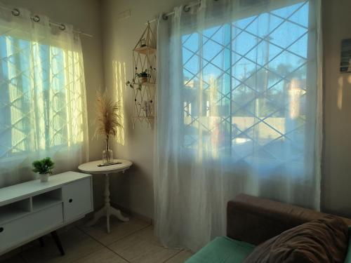 uma sala de estar com uma janela, uma mesa e um lavatório em Casa alguns passos do mar com piscina e SPA em Guaratuba