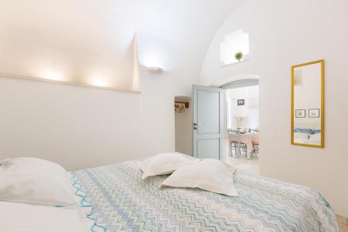 ein weißes Schlafzimmer mit einem Bett und einem Spiegel in der Unterkunft La Casetta Bianca by BarbarHouse in Locorotondo