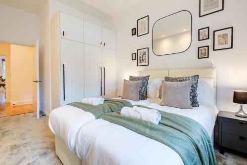 sypialnia z dużym białym łóżkiem z poduszkami w obiekcie Artsy Serviced Apartments - Ealing w Londynie