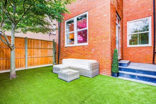a backyard with a white couch on the grass at Artsy Serviced Apartments - Ealing in London