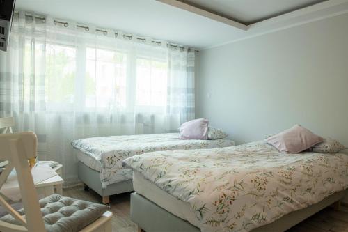 a bedroom with two beds and a window at Apartament Lawenda in Ciechocinek