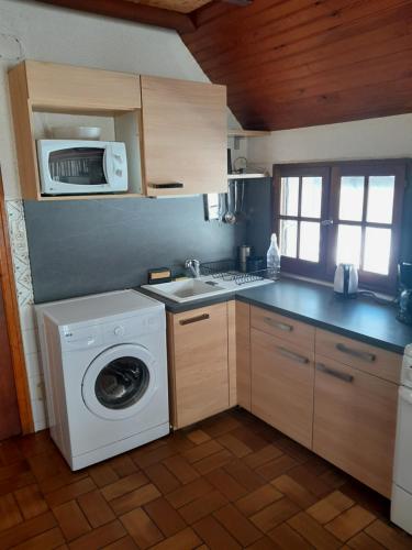 a kitchen with a washing machine and a microwave at Burguet in Campan