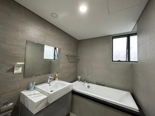 uma casa de banho com um lavatório, uma banheira e um espelho. em Căn hộ Vip 3 Phòng khu Diamond Celadon, ngay Aeon mall Tân Phú em Ho Chi Minh