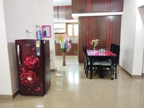 a dining room with a table and a refrigerator at SLS HOMESTAY - Luxury AC Service Apartments 1BHK, 2BHK, 3BHK - Direct Flyover to Alipiri Tirumala Gate - Walk to PS4 Pure Veg Restaurants, Supermarkets - Near to National Highway & Padmavathi Amma Temple - Modular Kitchen, Living room -Free Superfast Wifi in Tirupati