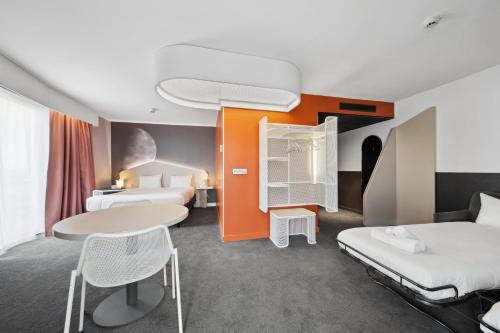 a hotel room with two beds and a table and chairs at ibis Styles Paris Charles de Gaulle Airport in Roissy-en-France