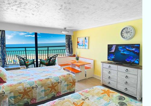 a bedroom with a bed and a television and a balcony at Ocean Reef- Unique Oceanfront Condo-Free parking - Amazing pools in Myrtle Beach