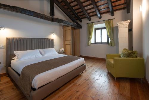 1 dormitorio con 1 cama grande y 1 silla en Lis Fadis Wine Relais, en Cividale del Friuli