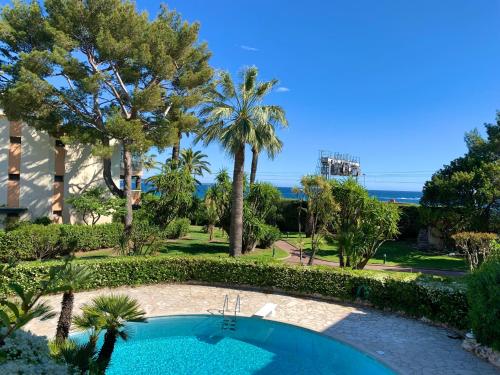 un complejo con piscina y palmeras en Appartement front de mer, 80M2 (3P), Piscine & Mer, en Cannes