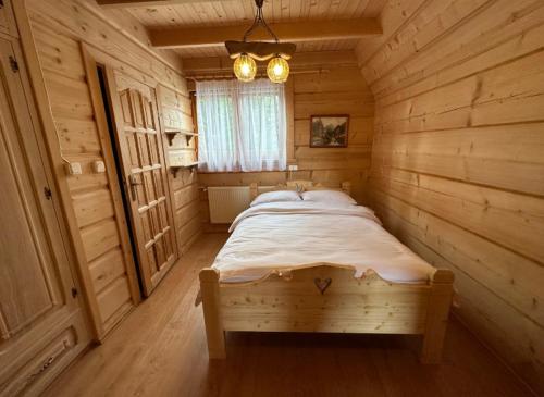 ein Schlafzimmer mit einem Bett in einem Holzzimmer in der Unterkunft JEDYNOCKA in Kościelisko