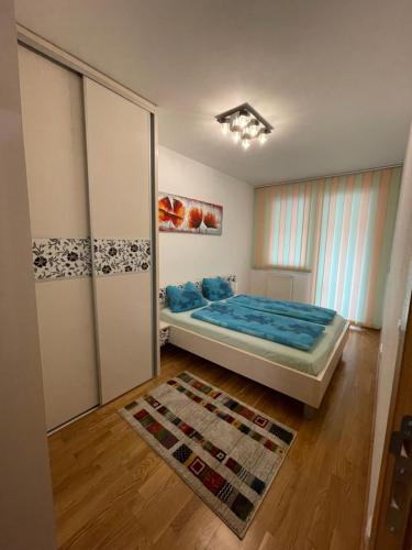 a bedroom with a bed with blue sheets and a rug at Sarajevo Apartment in Sarajevo