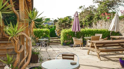 a patio with tables and chairs and umbrellas at Manorbier House - Lundy North Room in Tenby