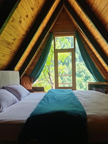 a bed in a room with a large window at Yayla Bungalov in Ayder Yaylasi