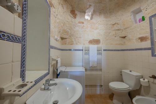 une salle de bain avec des toilettes blanches et un lavabo dans l'établissement Trullo nonna Pina, à San Michele Salentino