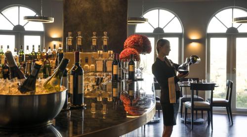 a woman standing at a bar with bottles of wine at Four Seasons Hotel The Westcliff in Johannesburg