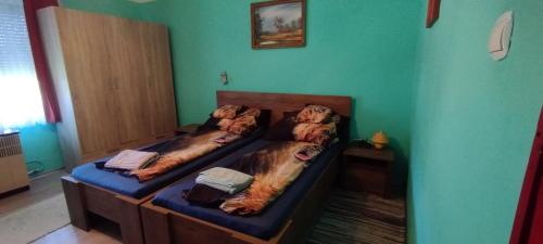 2 Betten in einem Zimmer mit grünen Wänden in der Unterkunft Kifog-Lak Vendégház in Poroszló