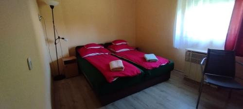 a bedroom with a bed with red sheets and towels at Kifog-Lak Vendégház in Poroszló