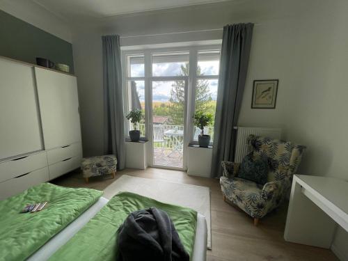 um quarto com uma cama, uma cadeira e uma janela em "Zur Erholung" in Jugendstilvilla Sonnenschein em Stolberg