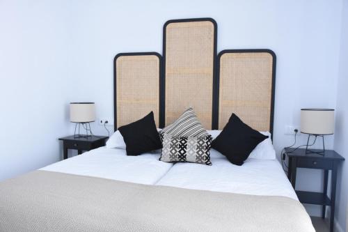 - un lit avec des oreillers en noir et blanc dans l'établissement CAPILLITA XXI APARTAMENTOS, à Sanlúcar de Barrameda