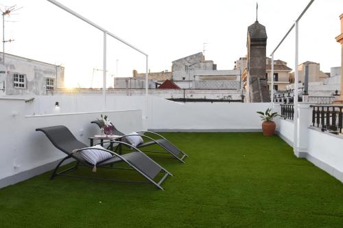 two chairs and a table on a balcony with green grass at CAPILLITA XXI APARTAMENTOS in Sanlúcar de Barrameda