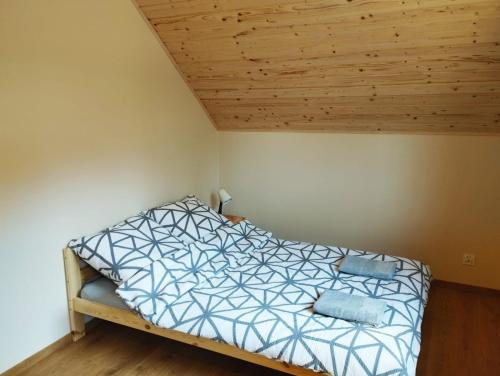 a bed in a room with a wooden ceiling at Domki Gorąca Bania in Gowidlino