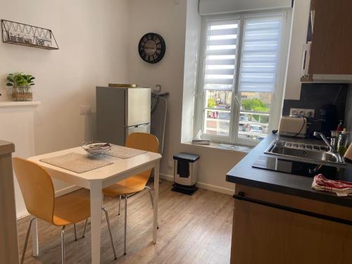 eine Küche mit einem Tisch und Stühlen sowie einem Kühlschrank in der Unterkunft Il y a de l'amour dans l'air - studio lit king size in Arromanches-les-Bains