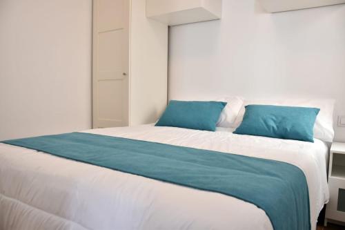 a bedroom with a large white bed with blue pillows at Casa Alex Torrevieja- Holiday House - con piscina comunitaria in Torrevieja