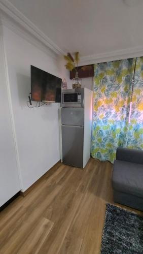 a living room with a refrigerator and a tv at Apartamento Céntrico cerca de la playa in Bueu