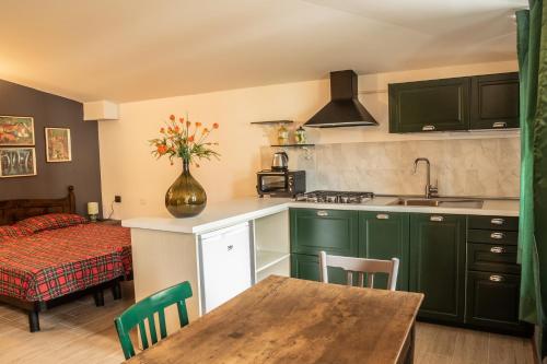 a kitchen with green cabinets and a table with a vase at Appartamenti Edolo - A 20 minuti da Ponte di Legno e Aprica in Edolo