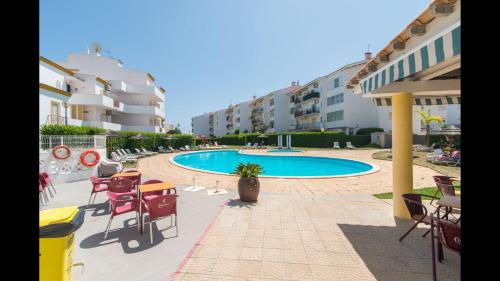 a patio with tables and chairs and a swimming pool at Apt Grace 2 Bedroom Apartment with Pool and Balcony, 2,5km from Tavira Center in Tavira