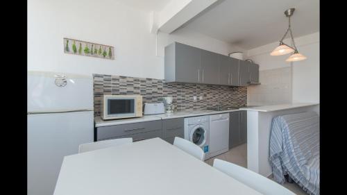 a small kitchen with a refrigerator and a microwave at Apt Grace 2 Bedroom Apartment with Pool and Balcony, 2,5km from Tavira Center in Tavira