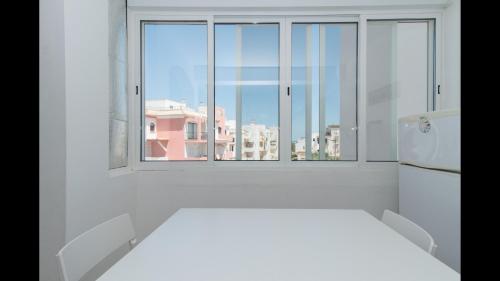 a white kitchen with a window and a white refrigerator at Apt Grace 2 Bedroom Apartment with Pool and Balcony, 2,5km from Tavira Center in Tavira