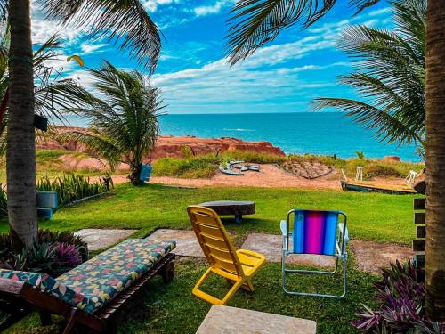 a patio with two chairs and a bench and the ocean at Raio de Sol Residence in Canoa Quebrada