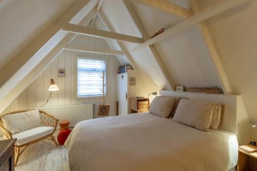 a bedroom with a white bed and a chair at CityCottage Alkmaar in Alkmaar