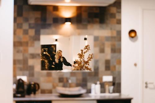 a woman standing in front of a mirror in a kitchen at Maas en Waal Wellness & Suites in Dreumel