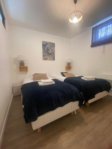 - une chambre avec 2 lits et des couvertures noires dans l'établissement La vie est belle - centre d'Arromanches, terrasse, à Arromanches-les-Bains