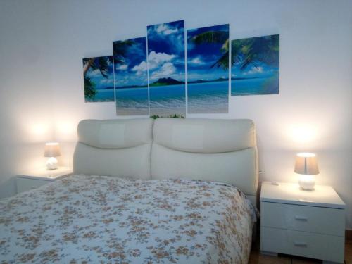 トッレ・ラピッロにあるVia Zanella Guesthouseのベッドルーム1室(壁に4つの絵画が飾られたベッド1台付)
