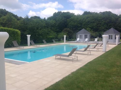 a swimming pool with chaises and chairs around it at Chateau De La Goujonnerie in Loge-Fougereuse