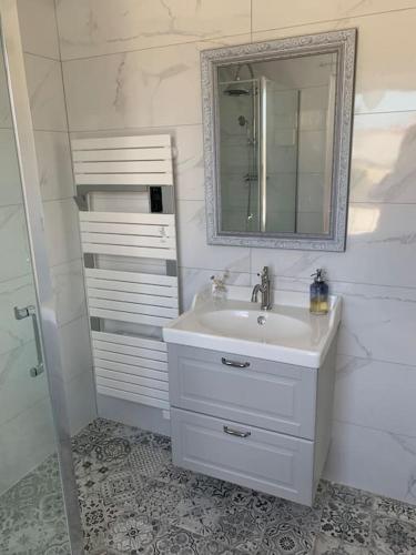 une salle de bain blanche avec un lavabo et un miroir dans l'établissement Pirou plage La Villa Mosca, à Pirou