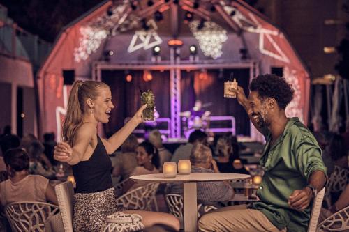 Un hombre y una mujer están aguantando las bebidas. en Hotel Astoria Playa Adults Only 4* Sup, en Puerto de Alcudia