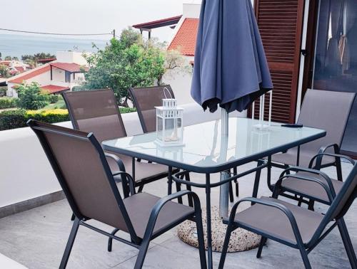 a glass table with chairs and an umbrella on a patio at Trikorfo Bungalows in Gerakini