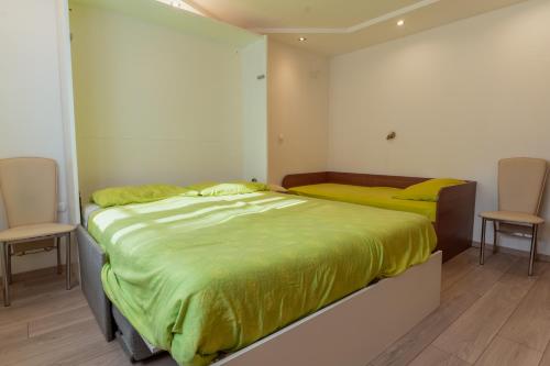 a bedroom with two beds with yellow sheets and two chairs at Studio Apartment Dominika in Ljubljana