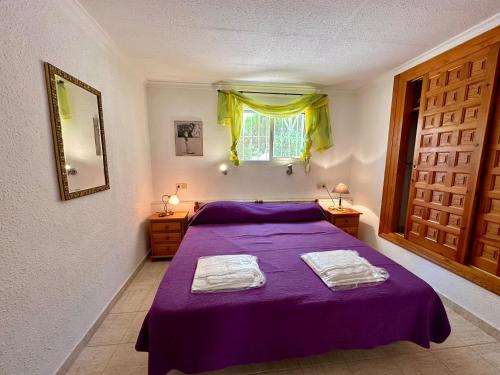 a bedroom with a purple bed with two towels on it at Apartamento Mar W3192 in Benitachell