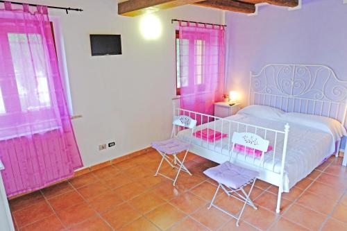 Schlafzimmer mit rosa Vorhängen, einem Bett und zwei Stühlen in der Unterkunft Il Parco in Ancona