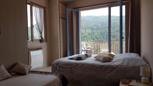ein Schlafzimmer mit einem Bett und einem großen Fenster in der Unterkunft Le Domaine de la Feuilleraie in Coaraze