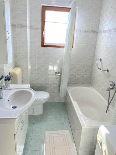a bathroom with a sink and a tub and a toilet at Olive Garden in Posedarje